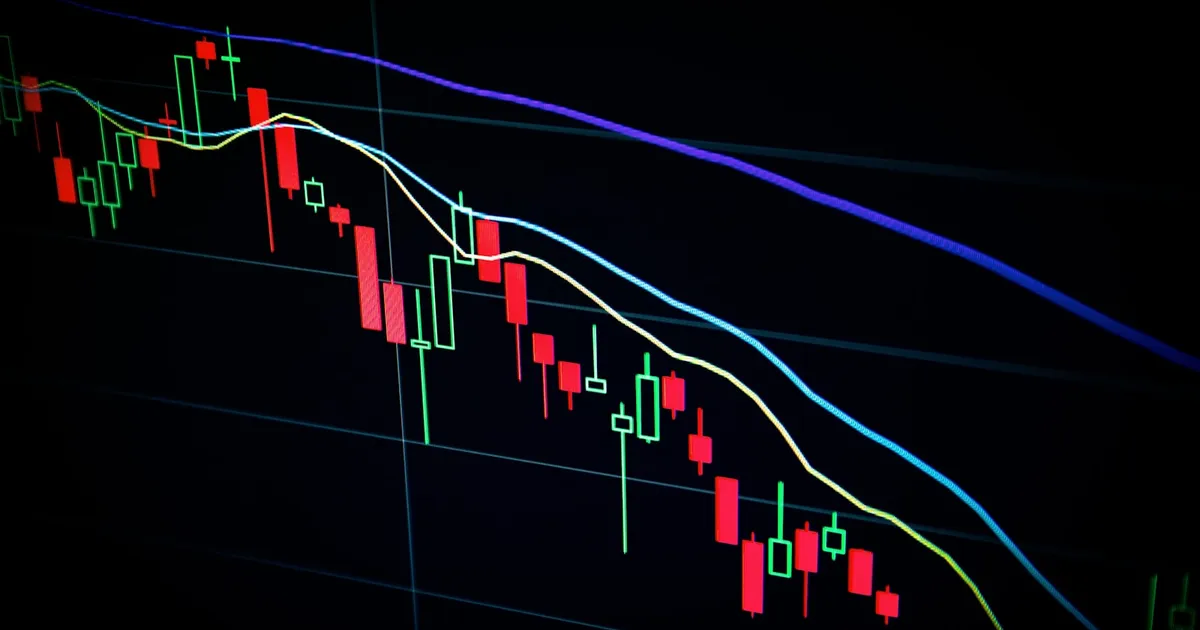 A declining candlestick chart in red and green on a dark screen