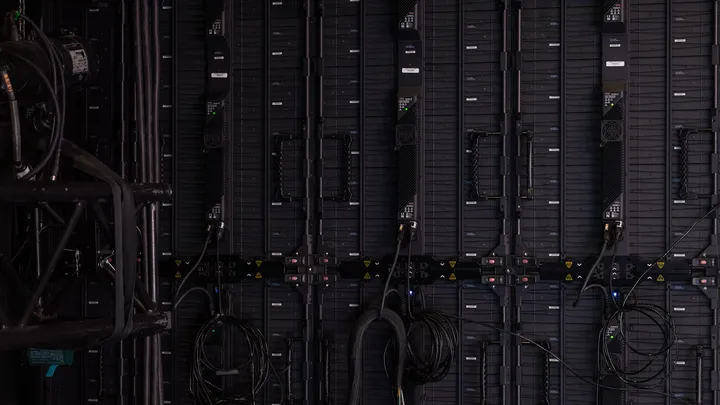 Rows of illuminated server racks in a data center aisle, representing AI cloud infrastructure