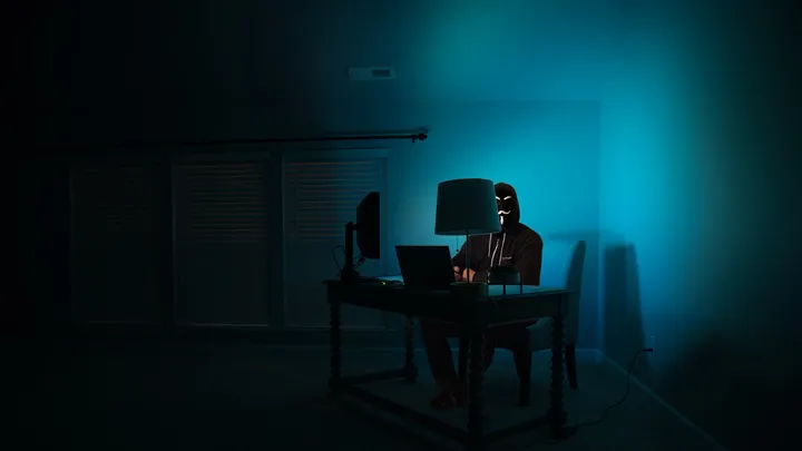 A dark room with multiple monitors displaying code