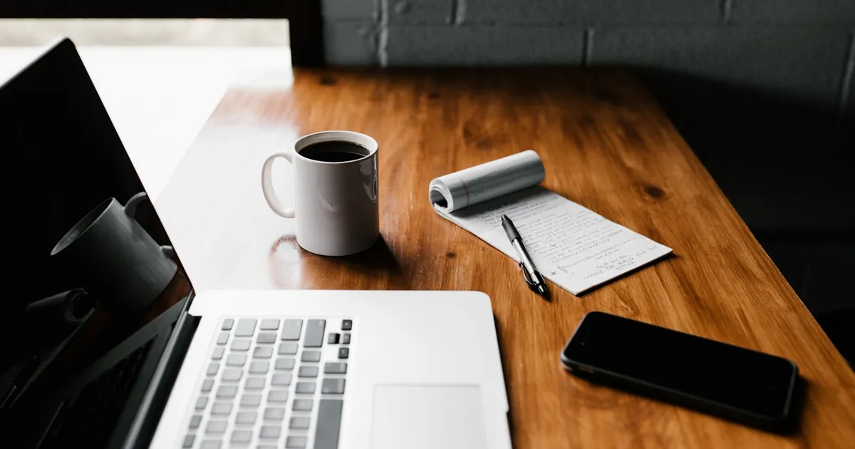 A laptop and notebook on a wooden desk