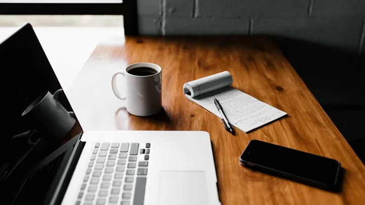 A laptop and notebook on a wooden desk