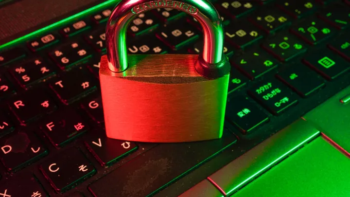 A padlock resting on a keyboard bathed in red light, representing an urgent security patch