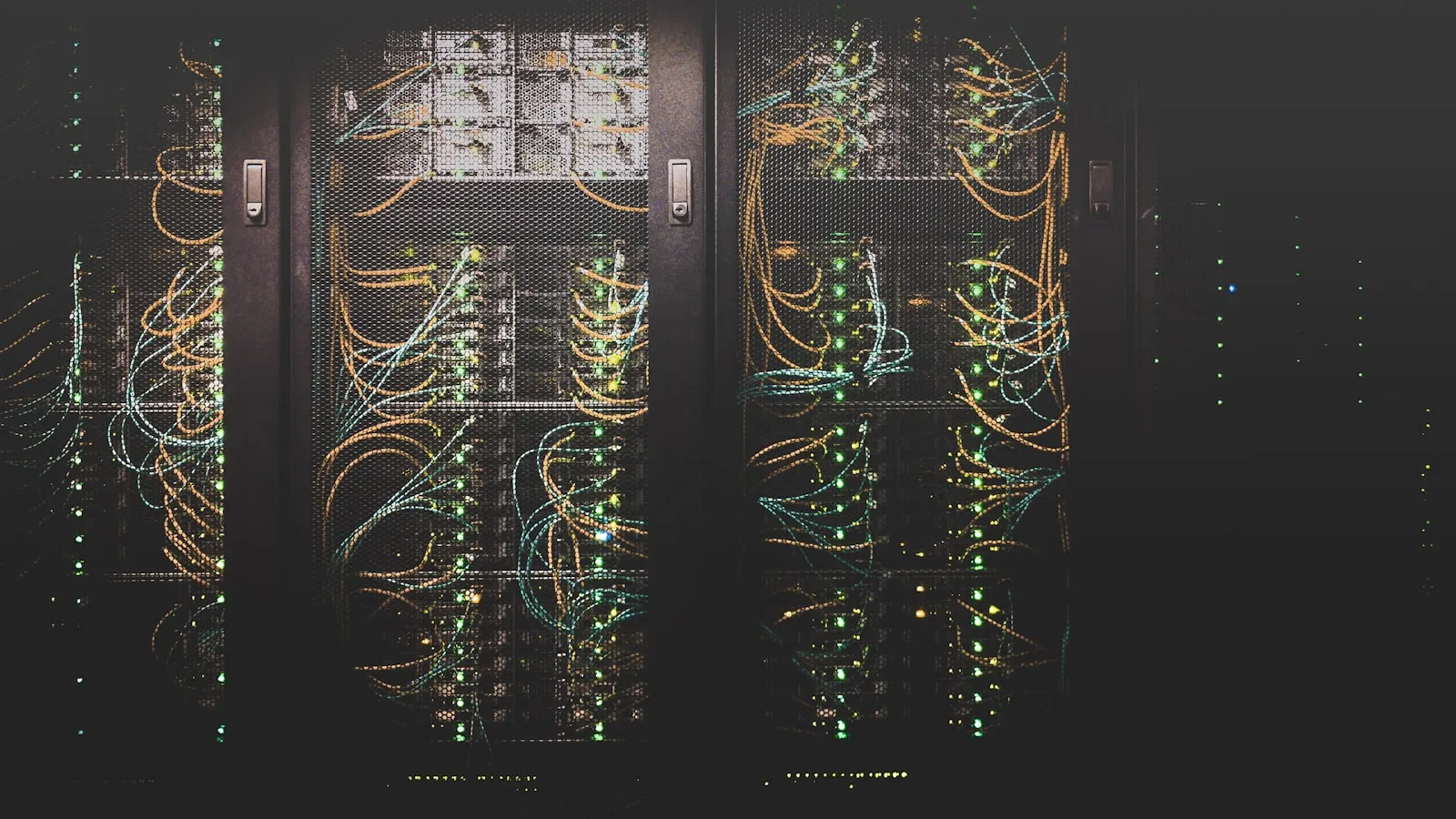 A dark server room with rows of networking equipment and blinking status lights