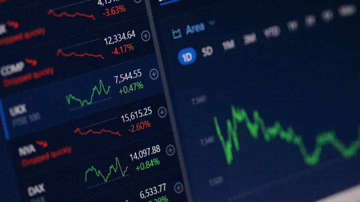 A financial trading dashboard showing rising charts and stock quotes on multiple screens