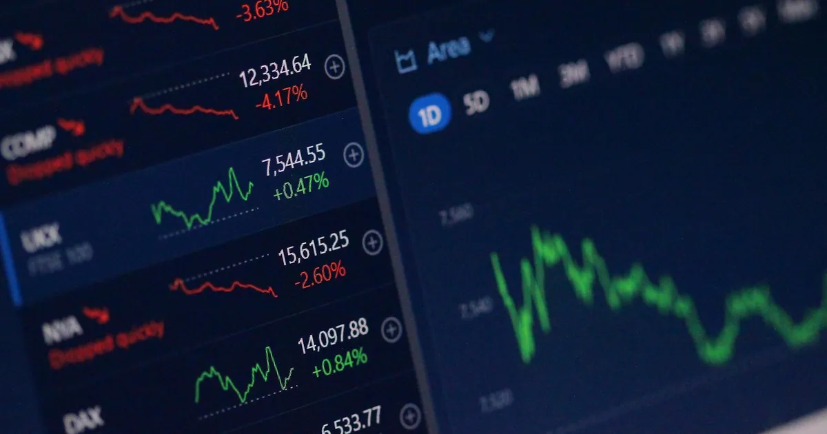 A financial trading dashboard showing rising charts and stock quotes on multiple screens