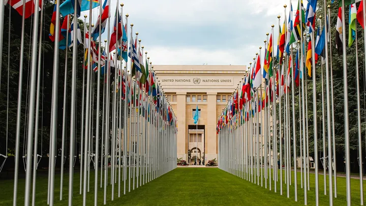 Rows of national flags outside an international institution, representing global cooperation on AI