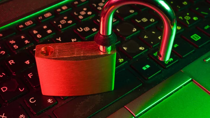 An open padlock resting on a laptop keyboard, symbolizing a compromised system